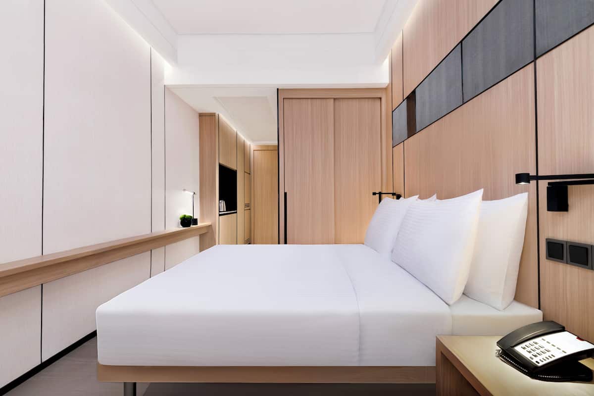 Une chambre d’hôtel moderne, dotée d’un grand lit, d’une table de chevet et d’un téléphone.
