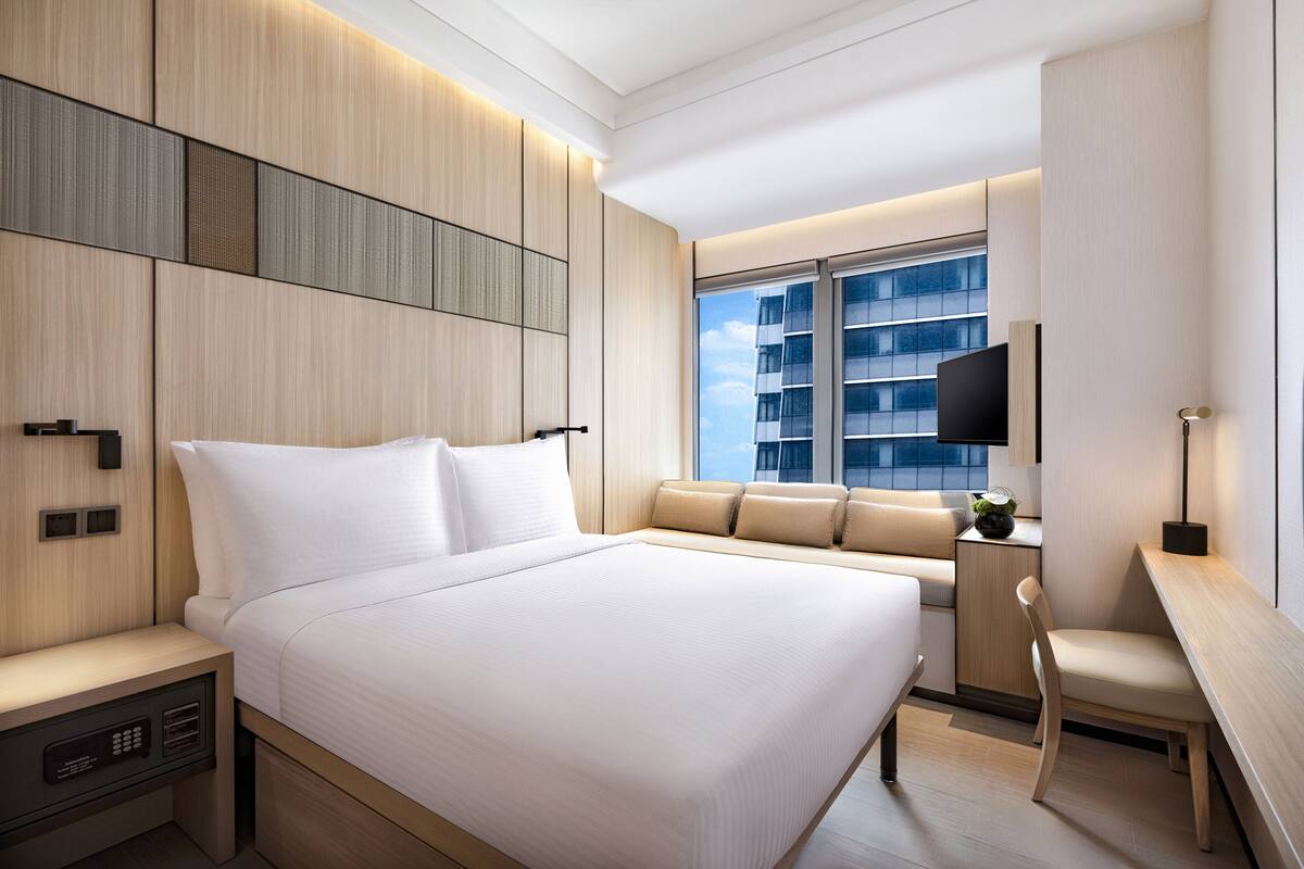 Une chambre d’hôtel moderne équipée d’un grand lit, d’un bureau, d’une chaise et d’un téléviseur.