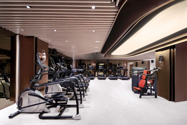 Un gimnasio moderno con cintas de correr, elípticas y equipo de pesas.