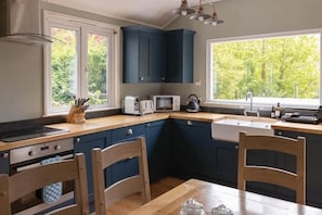 A kitchen with dark blue cabinets, a microwave, a toaster, and a sink.
