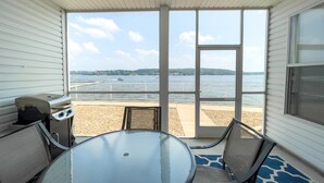 Eira coberta com mesa e cadeiras de vidro, com vista para a praia e para o mar.