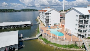 Um hotel à beira-mar com piscina, barcos atracados e um farol ao fundo.