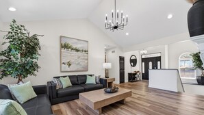 A modern living room with a sectional sofa, a wooden coffee table, a potted plant, and a painting on the wall. - Eagles Landing - Lakefront 5 Bdrm with Lakeside Tiki Bar (Sunrise Beach)