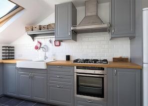 A modern kitchen with grey cabinets, a stainless steel range hood, a built-in oven, and a wooden countertop. - Spacious 3 bedrooms flat with terrace (London)
