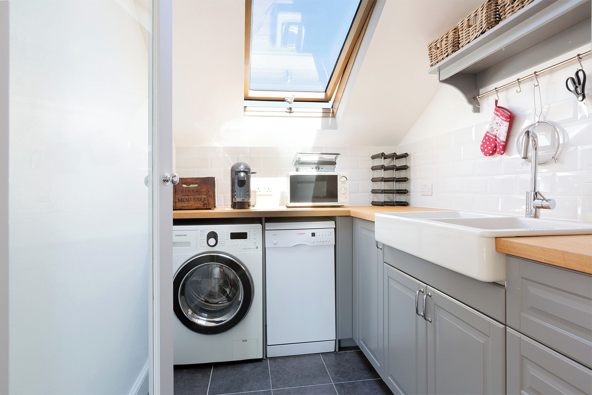 A compact kitchen with a washing machine, a microwave, and a sink.