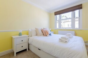 A bedroom with a bed, nightstand, and window. - Spacious 3 bedrooms flat with terrace (London)