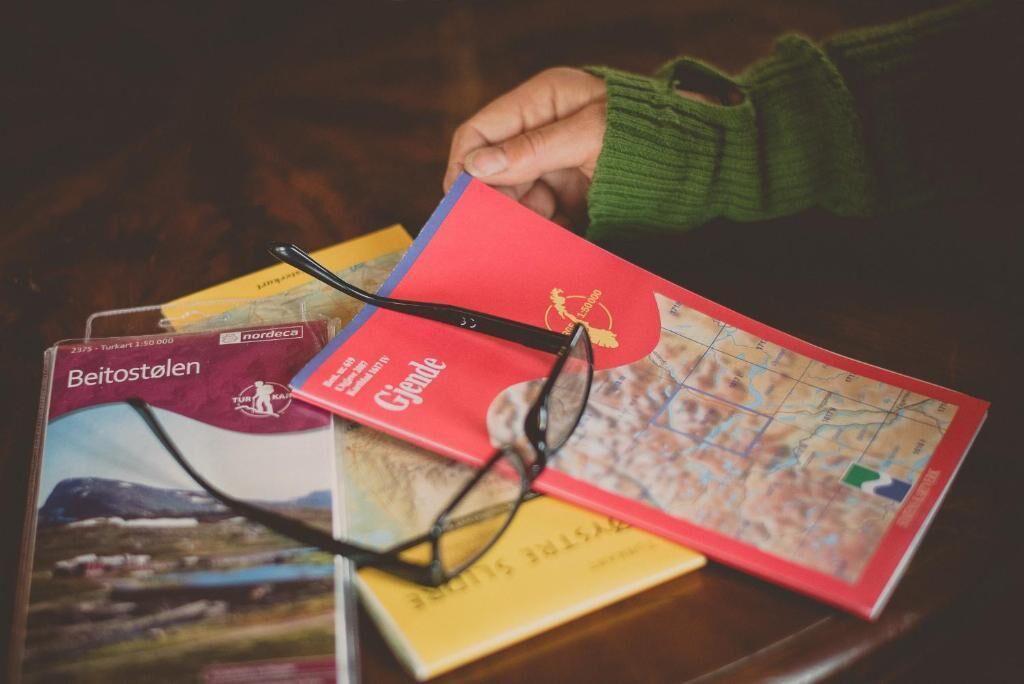 Una colección de mapas de viaje y un par de gafas sobre una mesa.