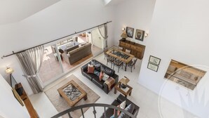 A spacious loft-style living area with a high ceiling, a dining area, and a kitchen visible through a glass door. - La Manga Club Los Olivos Apartment 593 (La Manga Club, Cartagena)