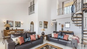 A spacious living room with two dark leather sofas, a wooden coffee table, and a staircase leading to an upper level. - La Manga Club Los Olivos Apartment 593 (La Manga Club, Cartagena)