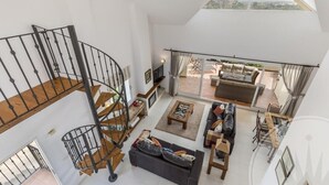 A spacious living area with a modern staircase, a sofa set, and a balcony with outdoor furniture. - La Manga Club Los Olivos Apartment 593 (La Manga Club, Cartagena)