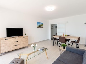 A modern living room with a flat-screen TV, wooden cabinet, glass coffee table, and a gray sofa. - Les Trois Caps by Interhome (Cagnes-sur-Mer)