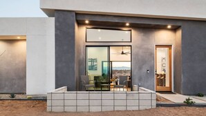 A modern building with a large glass door, a seating area with chairs, and a view of the landscape.