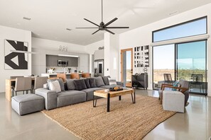 A modern living room with a sectional sofa, a coffee table, and a large window offering a view of the outdoors.