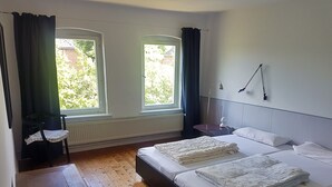 Un dormitorio con dos camas, una silla, una mesa y una ventana con cortinas.