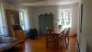 Una sala de estar acogedora con una mesa de comedor de madera, un sofá y un amplio ventanal.