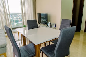 A modern hotel room with a large window, a flat-screen TV, a small plant, and a calendar on the wall. - Elegant And Restful 2Br At Menteng Park Apartment (Jakarta)