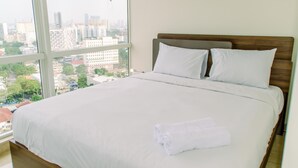 A hotel room with a large bed, two pillows, and a neatly folded towel. - Elegant And Restful 2Br At Menteng Park Apartment (Jakarta)