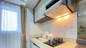 A modern kitchen with a gas stove, a dish rack, and a patterned backsplash. - Spacious And Homey 2Br Apartment At Newton Residence (Bandung)