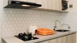 A kitchen with a gas stove, a kettle, and a sink.