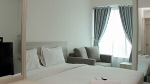A hotel room with a large bed, a sitting area, and a window with curtains.