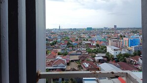 Visão urbana pela janela, com edifícios de diversas cores e estilos arquitetônicos.
