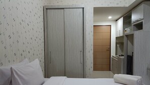 Quarto de hotel com cama, armário e banheiro.