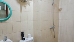 Casa de banho com lavatório, sanita e chuveiro.