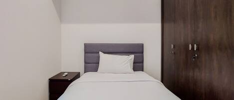 A bedroom with a bed, a nightstand, and a wardrobe.