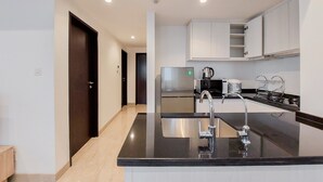 A modern kitchen with a black countertop, stainless steel appliances, and white cabinets. - Spacious 2Br At Branz Bsd Apartment (Pagedangan)