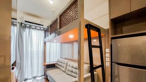 Un salon moderne avec un canapé, une échelle et un réfrigérateur.