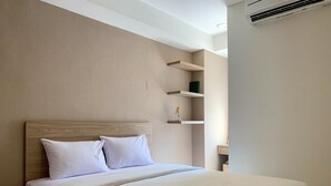 A neatly made bed with a wooden headboard, white bedding, and a folded towel on the bed. - Comfort And Tidy 2Br At Cinere Bellevue Suites Apartment (Depok)