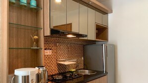 A compact kitchen with a modern design, featuring a stainless steel refrigerator, a coffee maker, and a kettle on the counter. - Comfort And Tidy 2Br At Cinere Bellevue Suites Apartment (Depok)