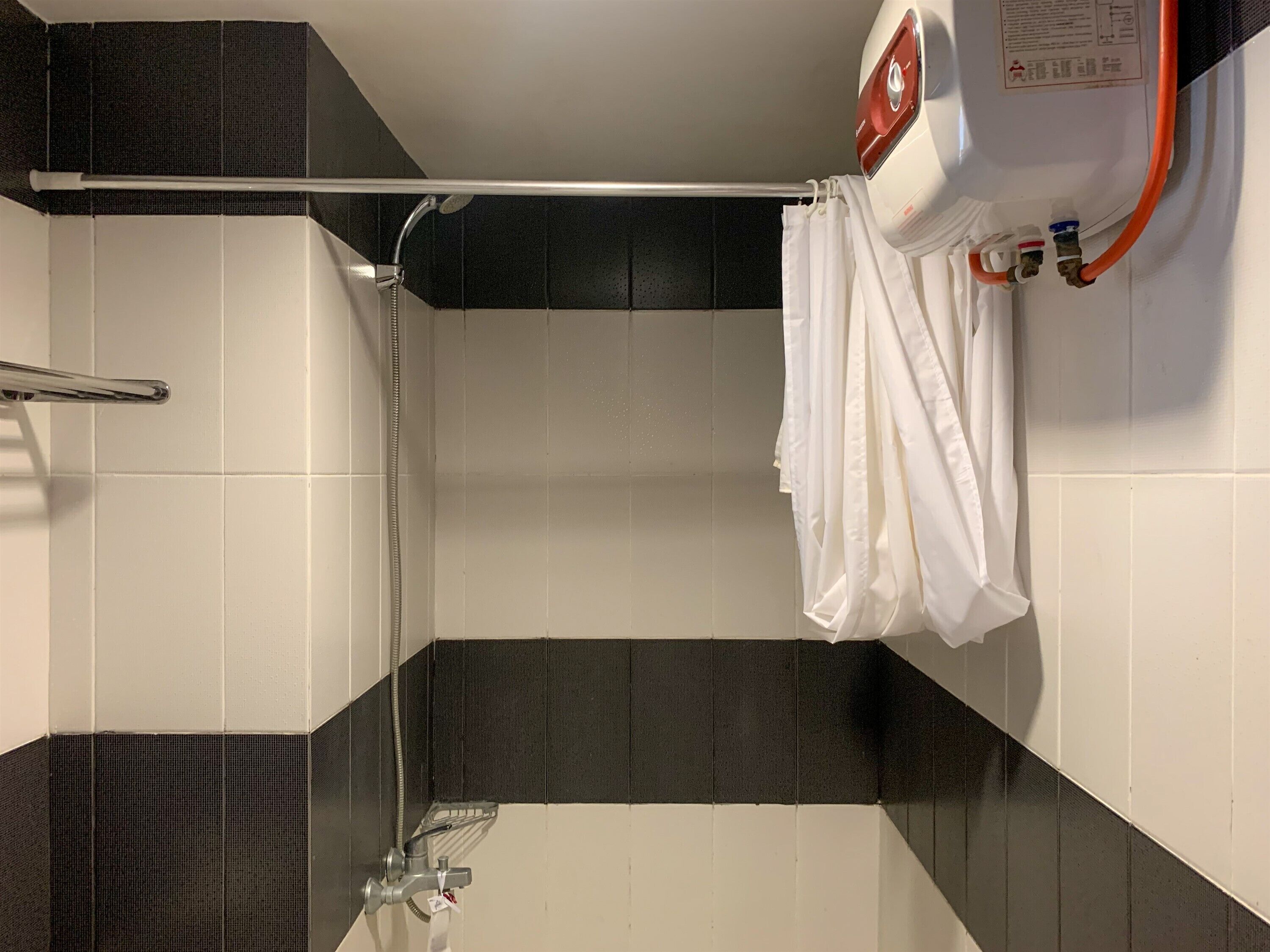 Uma casa de banho moderna com chuveiro, porta-toalhas e termoacumulador.
