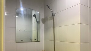Une salle de bain avec une douche, un miroir et des murs carrelés.