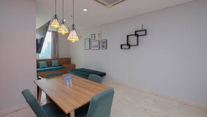 A dining area with a wooden table, green upholstered chairs, and hanging pendant lights.