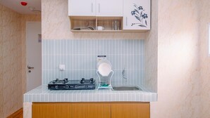 A compact kitchen with a gas stove, a coffee maker, and a sink. - Nice And Cozy Studio At La Hub City Apartment (Jakarta)