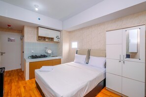 A hotel room with a bed, a wardrobe, a small kitchenette, and a bathroom. - Nice And Cozy Studio At La Hub City Apartment (Jakarta)