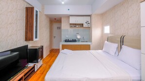 A hotel room with a bed, a TV, a desk, and a kitchenette. - Nice And Cozy Studio At La Hub City Apartment (Jakarta)