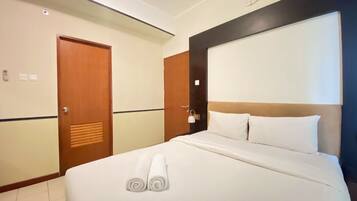 Habitación de hotel con cama, puerta de madera, interruptor de luz y aire acondicionado instalado en la pared.