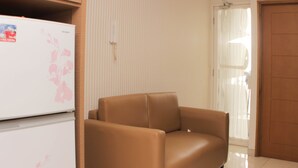 A room with a brown sofa, a white refrigerator with a floral sticker, and a door with a towel hanging on it. - Best Deal 2Br Apartment At Cinere Bellevue Suites (Depok)