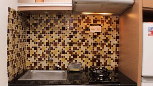 A kitchen with a tiled backsplash, a stainless steel sink, a gas stove, and a white refrigerator. - Best Deal 2Br Apartment At Cinere Bellevue Suites (Depok)