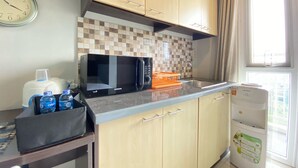 A kitchen with a microwave, water dispenser, and a clock on the wall. - Cozy Studio Room At Skyland City Jatinangor Apartment (Hegarmanah)