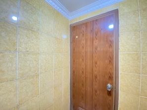 Bathroom features a tiled wall and a door with a metallic handle.