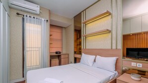 A hotel room with a bed, bedside table, TV, and a desk with a chair.