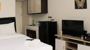 Habitación de hotel con cama, televisión, refrigerador, kitchenette y armario.