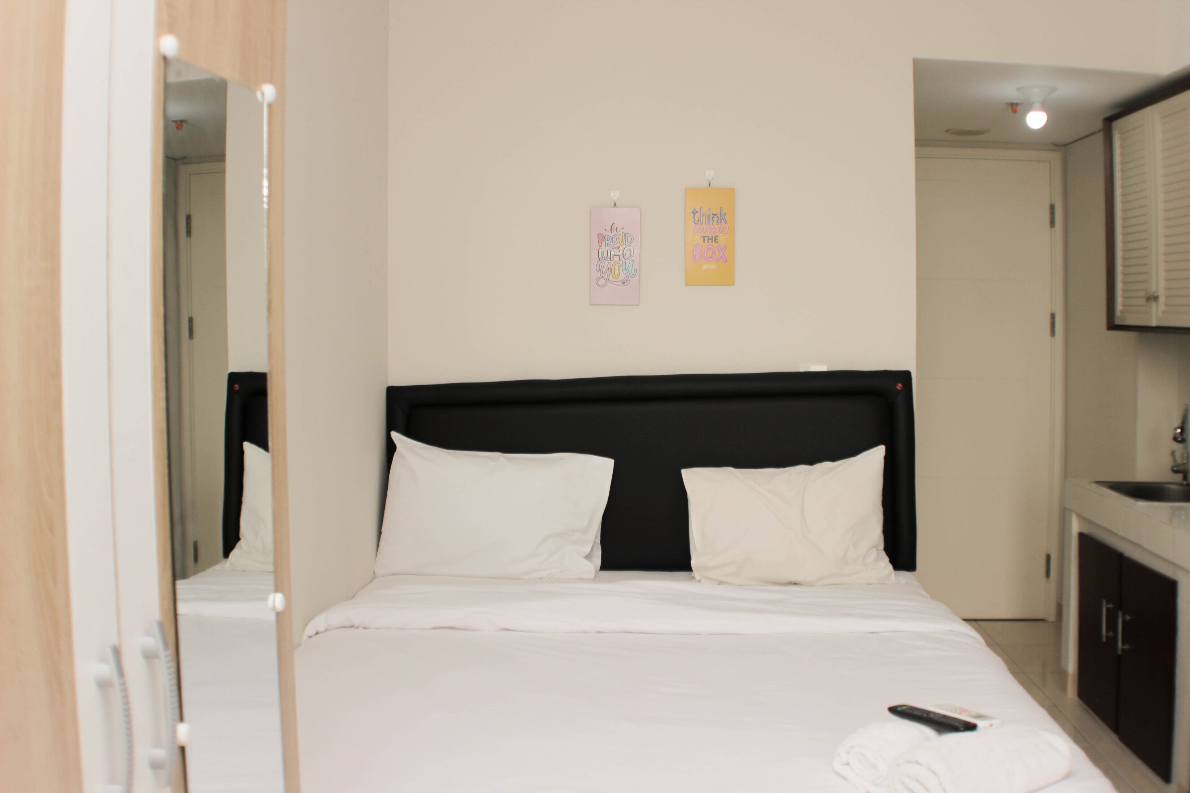 Habitación de hotel con cama, espejo, lavamanos y dos adornos en la pared.