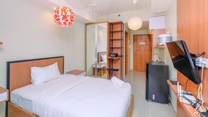 Moderni hotellihuone, jossa on sänky, yöpöydät, työpöytä tietokoneella, televisio ja vaatekaappi.