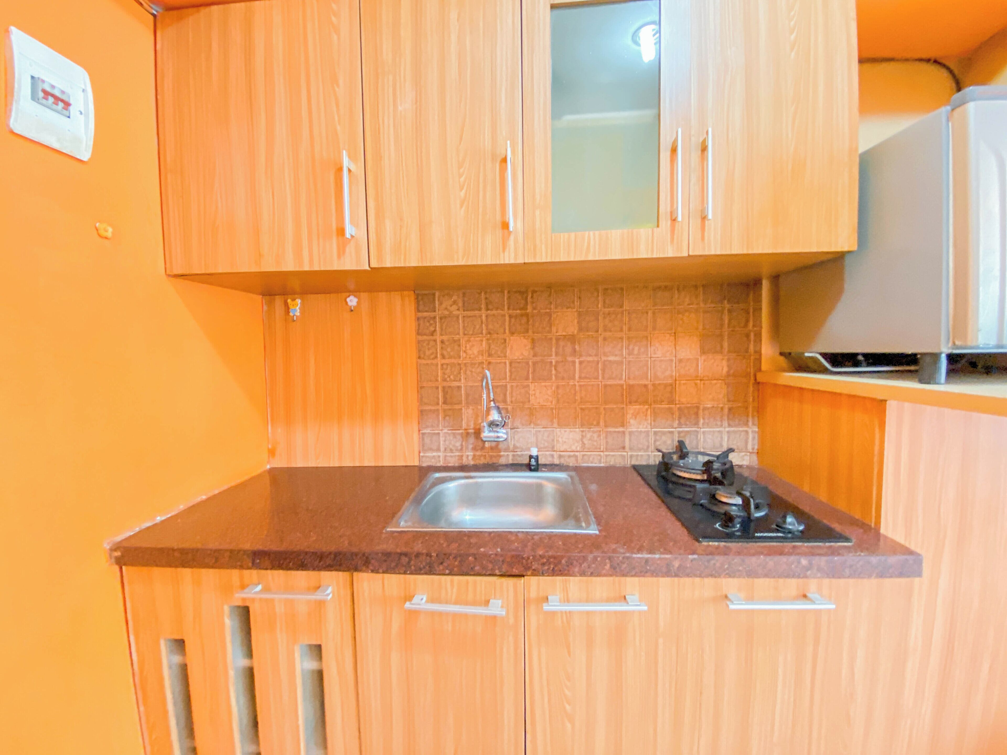 A kitchen with wooden cabinets, a tiled backsplash, a stainless steel sink, and a stove.