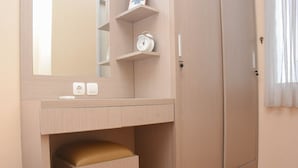 A bedroom with a wooden wardrobe, a bedside table with a lamp, and a mirror. - Enjoy Living And Tidy 1Br Bassura City Apartment (Jakarta)