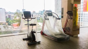 Ein Fitnessstudio mit Trainingsgeräten, großen Fenstern und Blick auf die Stadt.